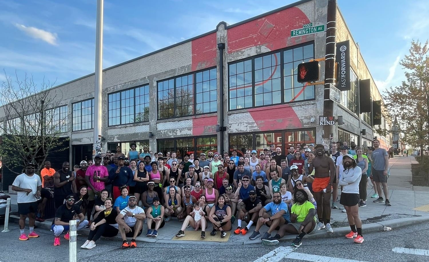 A large group of runners posing for a photo on a street in front of a city building