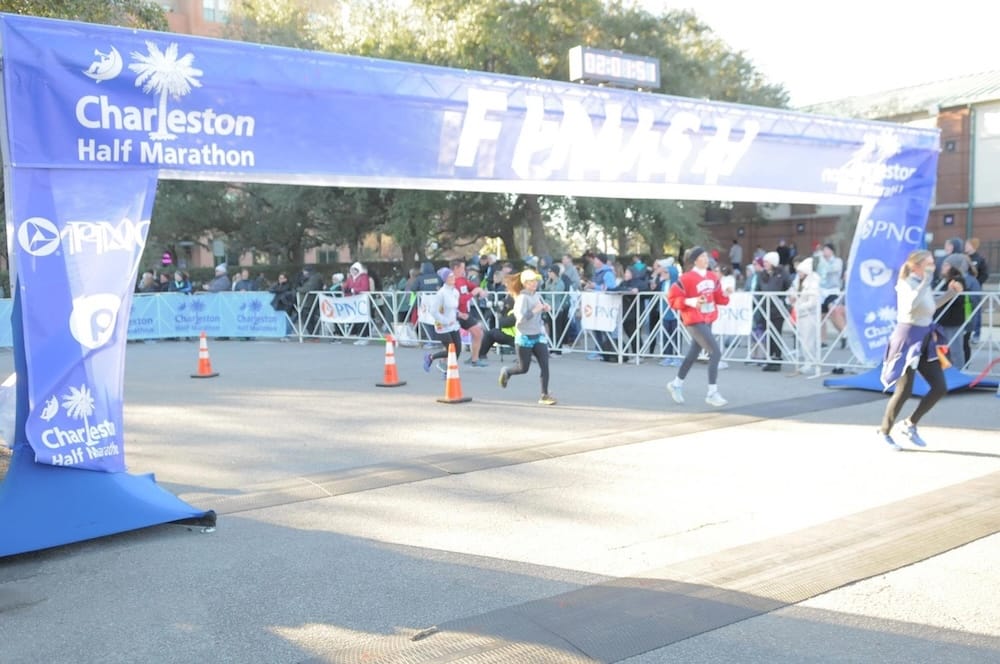 Several runners crossing the finish line of a race with a blue finish line banner overhead