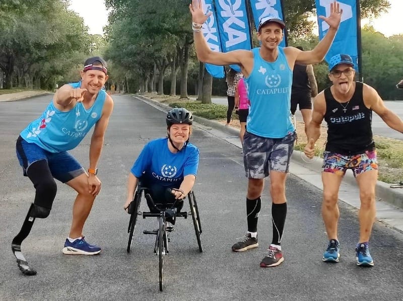 Four adaptive athletes wearing team jerseys and posing for a photo outside