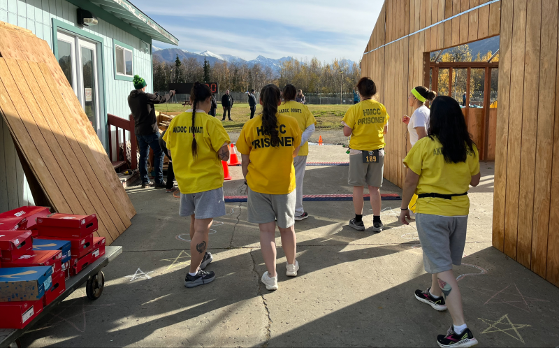 Several women runners in yellow shirts ready to start a race on the outdoors grounds of a women's correctional center