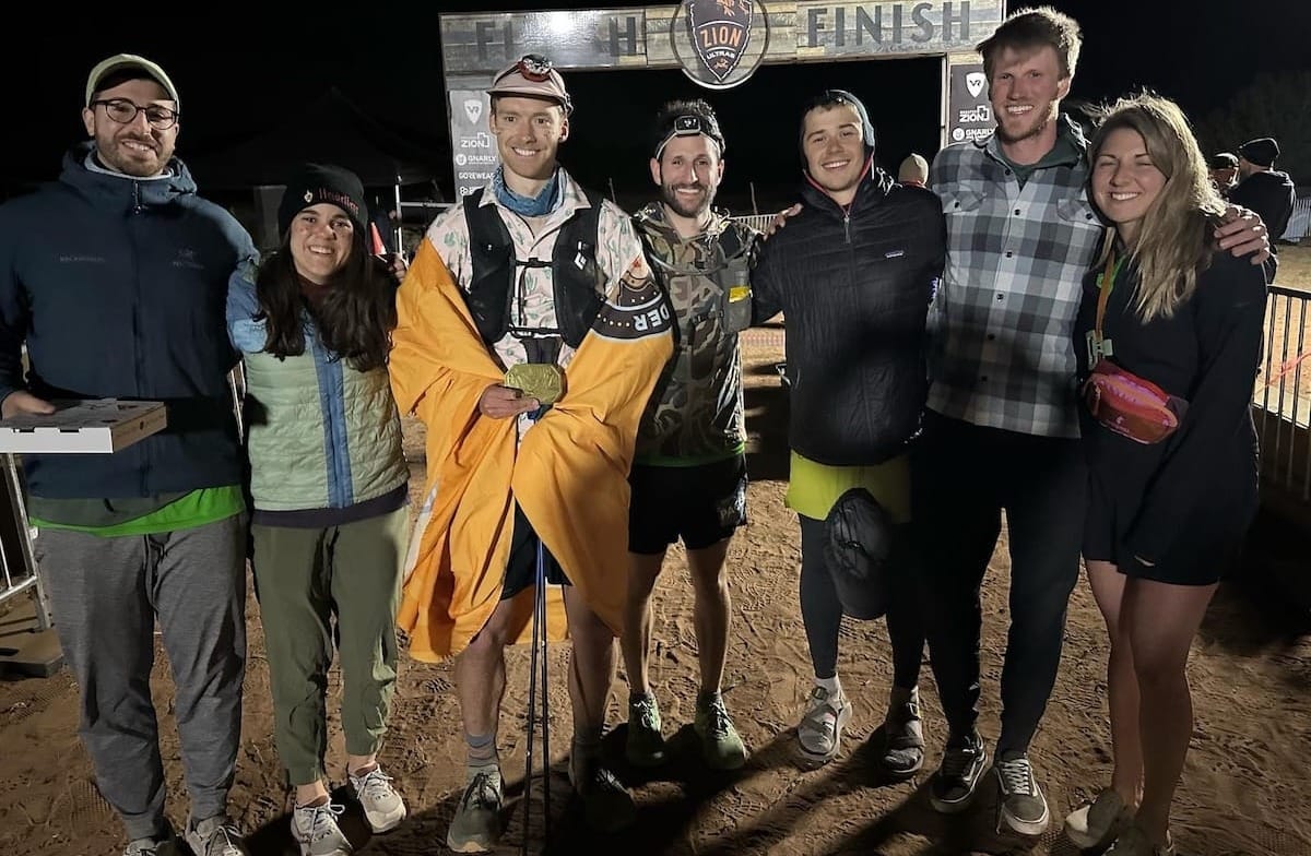 A group of people standing in front of a race finish line outside in the dark