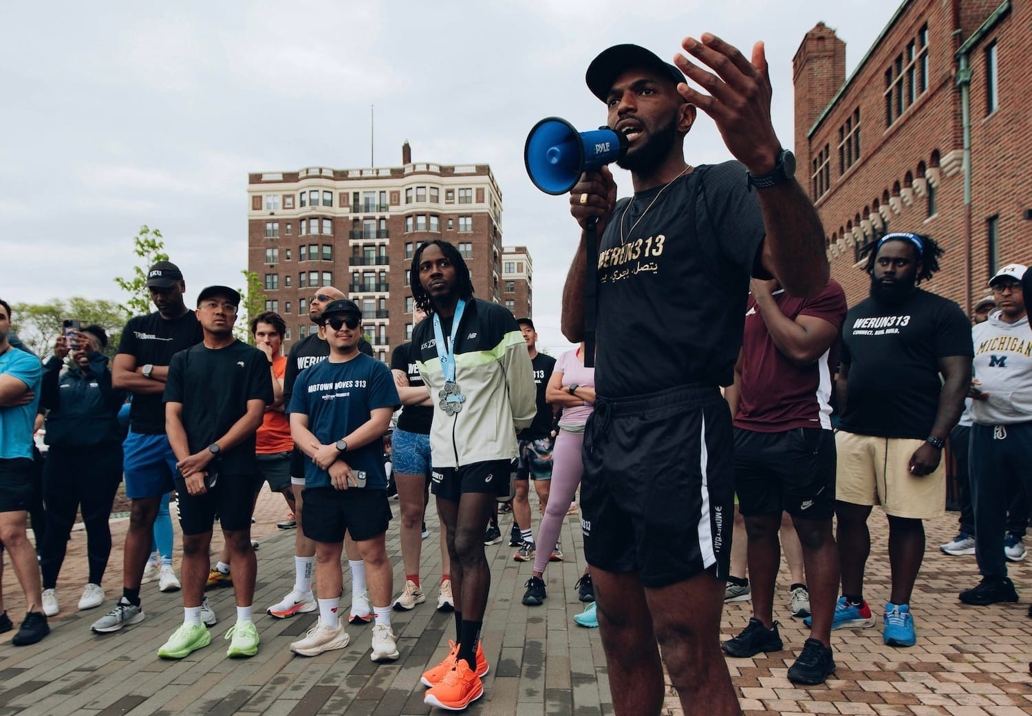 A group of runners gathering outside around a runner talking through a megaphone