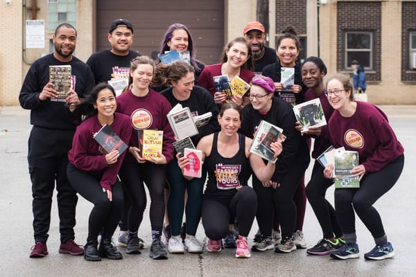 A group of runners in black and maroon apparel, posing for a group photo outdoors and each holding a book