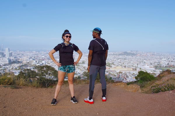 A man and a woman standing on top of a downtown city overlook