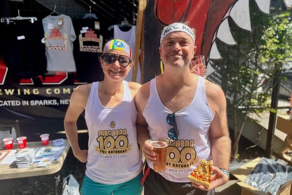 Two runners posing outside on a sunny day, wearing white tank tops, with one runner holding a beer in one hand and a slice of pizza in the other hand