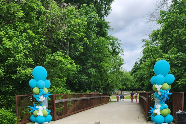 A bridge walkway with balloons and green trees on both sides