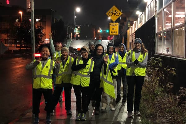 A group of runners wearing bright safety vests posing outside in the dark for a photo